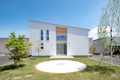 メインに白い外壁と上下にラインが走るように明るいブラウンの外壁を張り分けた片流れの外観