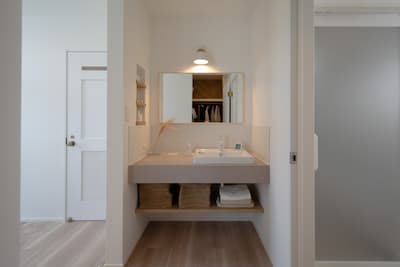 洗面ボウルと小物をおいて置けるスペースを設けたニュアンスカラーの幅広洗面台