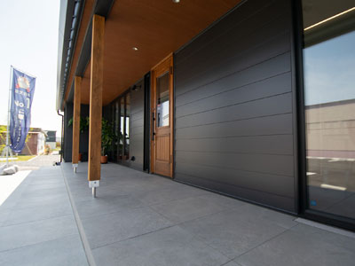 石目調の大判タイルで広めにとったポーチと階段に木目調の軒天・柱・扉を組み合わせたかっこいい外観