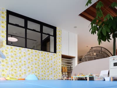 打ち合わせスペースとを仕切る壁に室内窓を設けたフロアマット敷きのキッズルーム